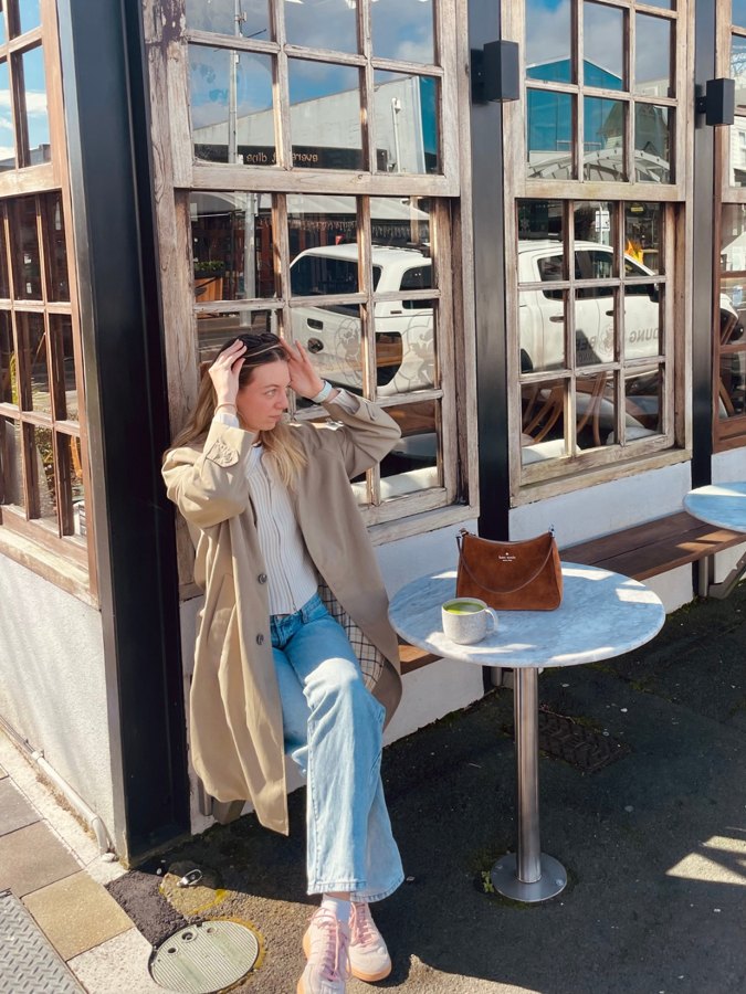Emma with a matcha at a café table in Auckland